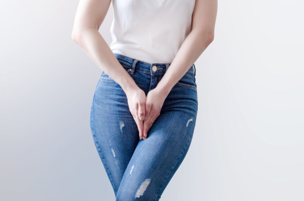 Junge frau mit Jeans hat Probleme mit Inkontinenz
